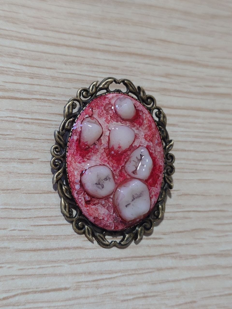 Broche de teratoma con marco dorado, modelo B, vista frontal en perspectiva