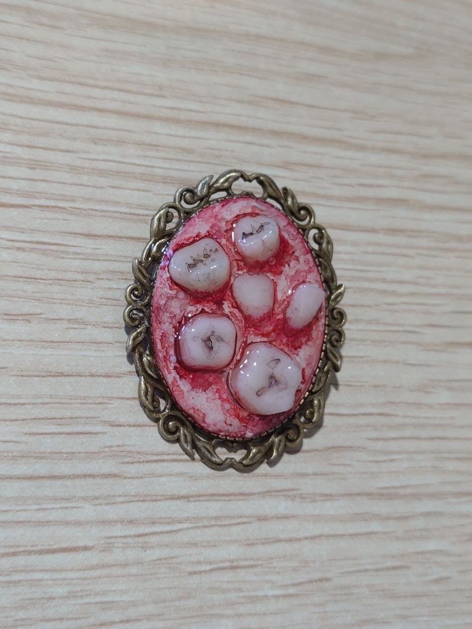 Broche de teratoma con marco dorado, modelo C, vista frontal en perspectiva