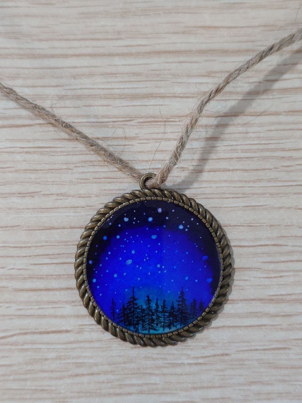 Collar artesanal con escena de bosque azul y marco dorado, vista completa